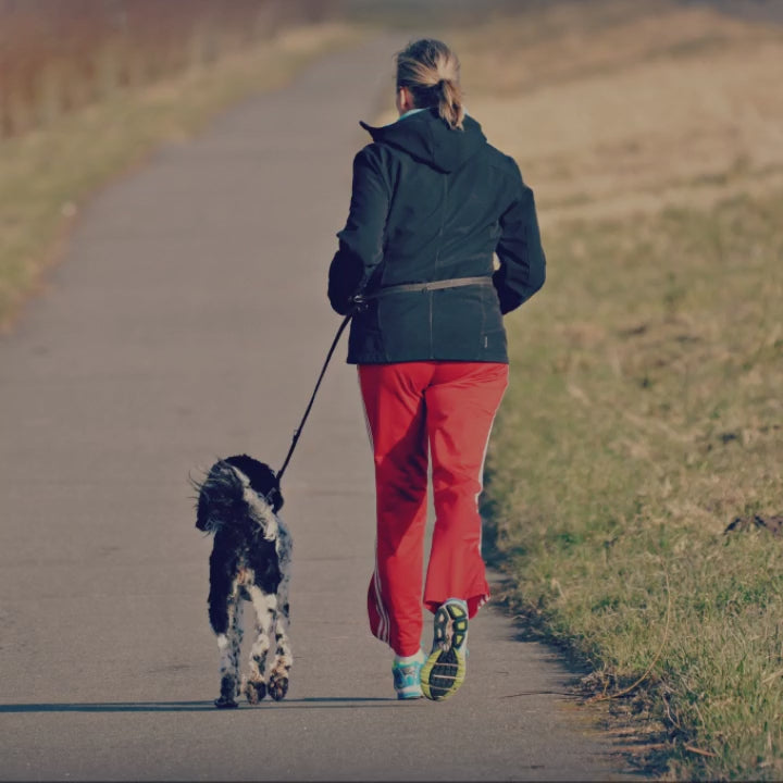 Woman running with her dog on a paved walking path