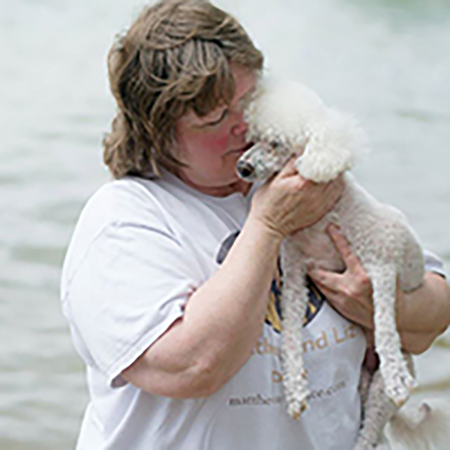 Woman hugs her little white dog and presses their faces together